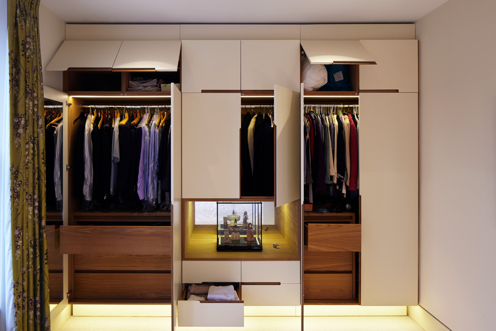 This is an example of a contemporary gender-neutral built-in wardrobe in London with flat-panel cabinets and white cabinets.