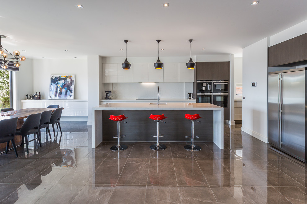 This is an example of a mid-sized contemporary single-wall eat-in kitchen in Melbourne with an undermount sink, glass-front cabinets, white cabinets, white splashback, stainless steel appliances, with island, brown floor and porcelain floors.