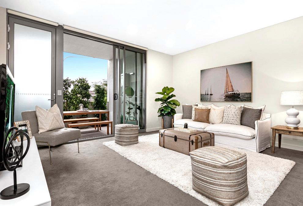 This is an example of a beach style living room in Sydney with beige walls, carpet and grey floor.