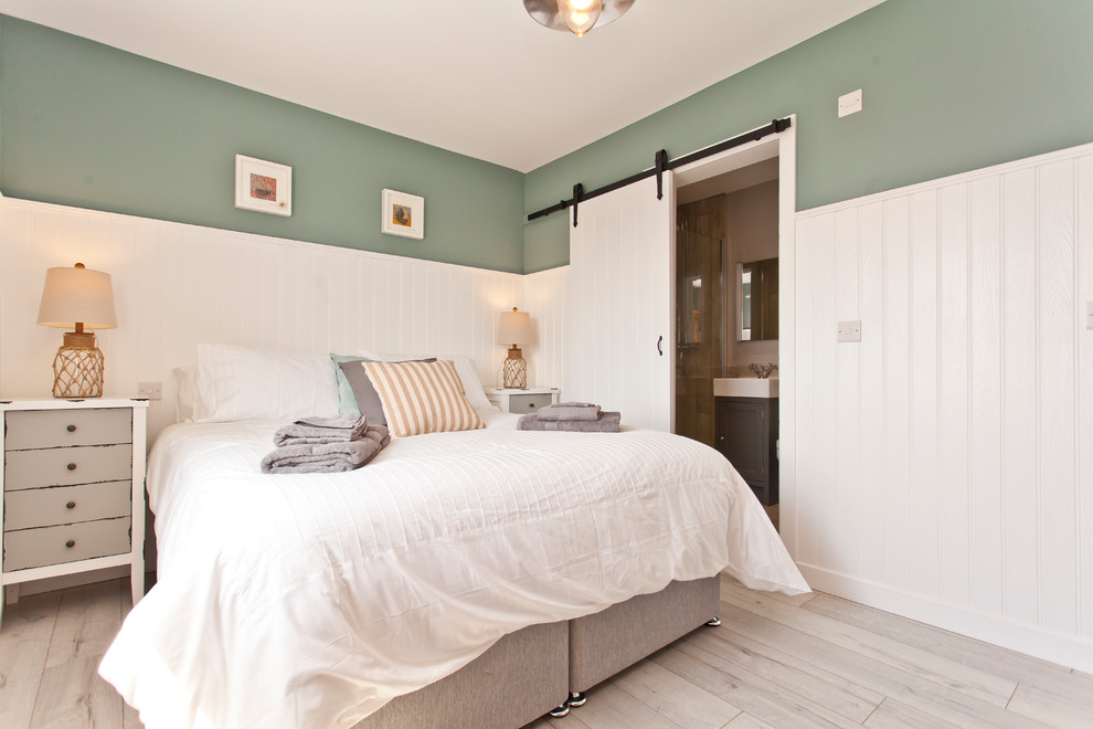 Photo of a mid-sized beach style bedroom in Dorset with green walls and grey floor.