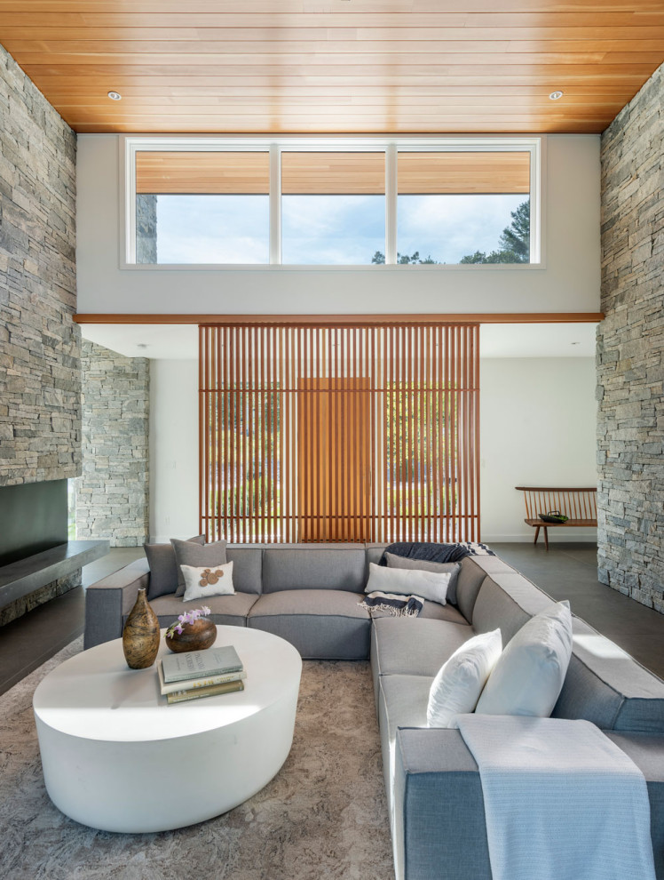 This is an example of a midcentury open concept living room in Boston with white walls, ceramic floors, a stone fireplace surround, grey floor and wood.