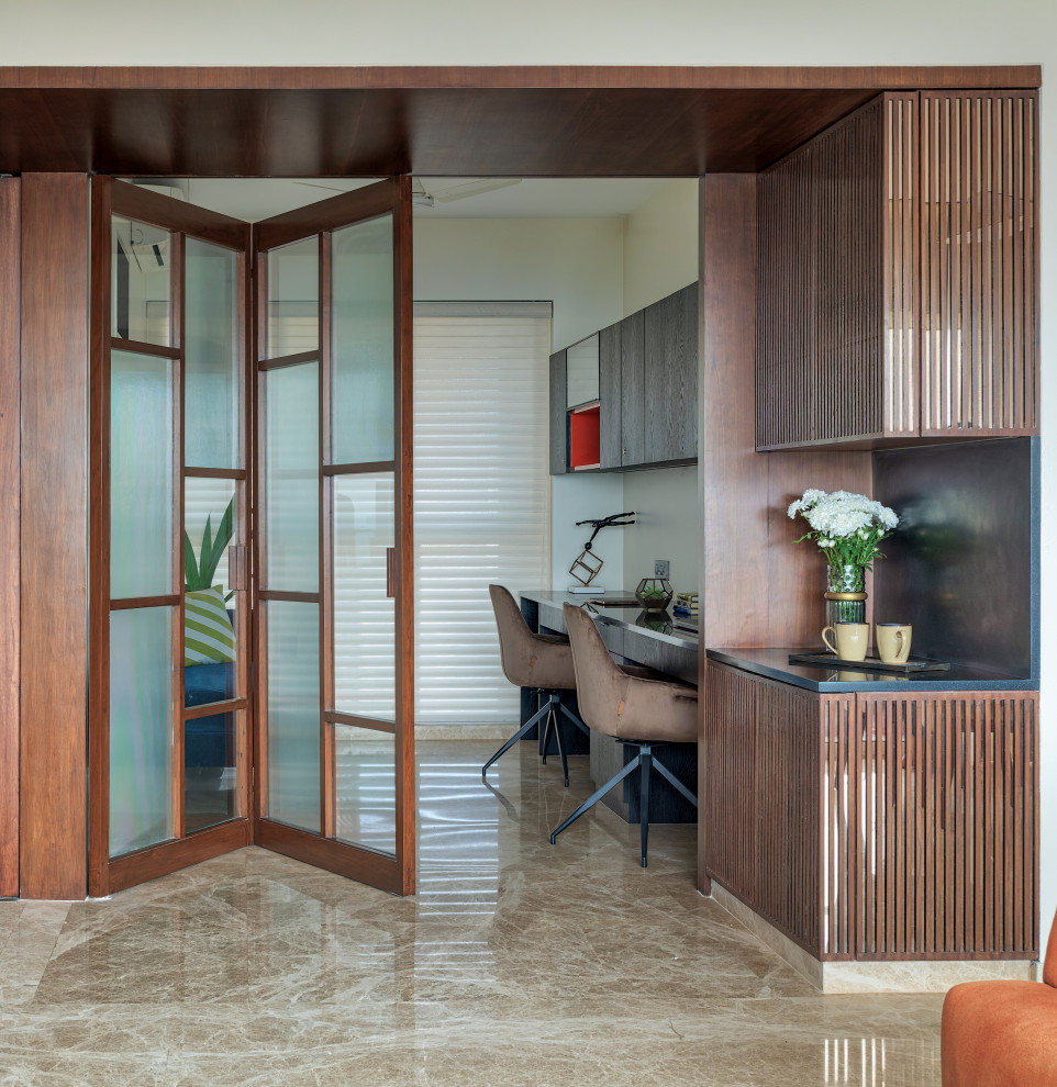 Contemporary home office in Mumbai with beige walls, a built-in desk and beige floor.