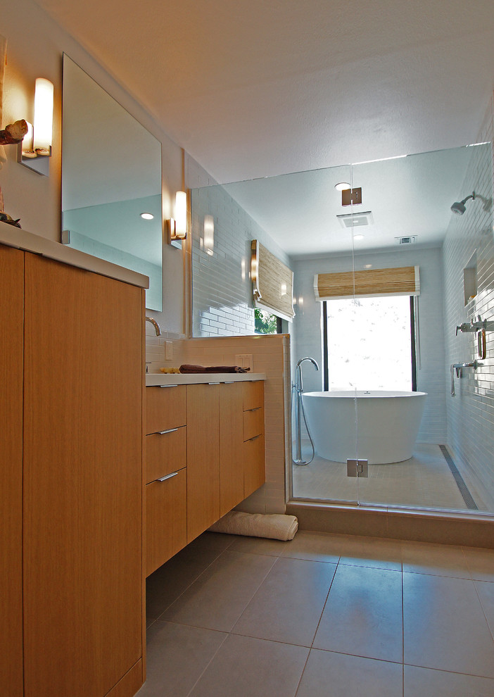 This is an example of a mid-sized modern master wet room bathroom in San Francisco with flat-panel cabinets, light wood cabinets, a japanese tub, a wall-mount toilet, white tile, subway tile, white walls, porcelain floors, an undermount sink, engineered quartz benchtops, grey floor, a hinged shower door and beige benchtops.