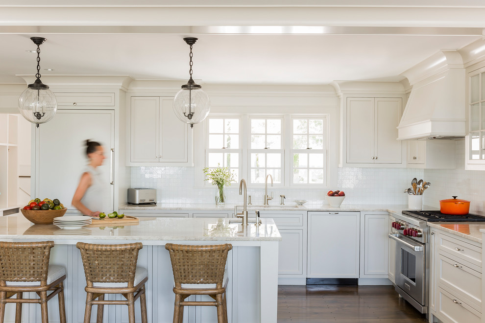 Inspiration for a beach style kitchen in Boston with marble benchtops, white splashback, ceramic splashback, stainless steel appliances, medium hardwood floors, with island, an undermount sink, recessed-panel cabinets and white cabinets.