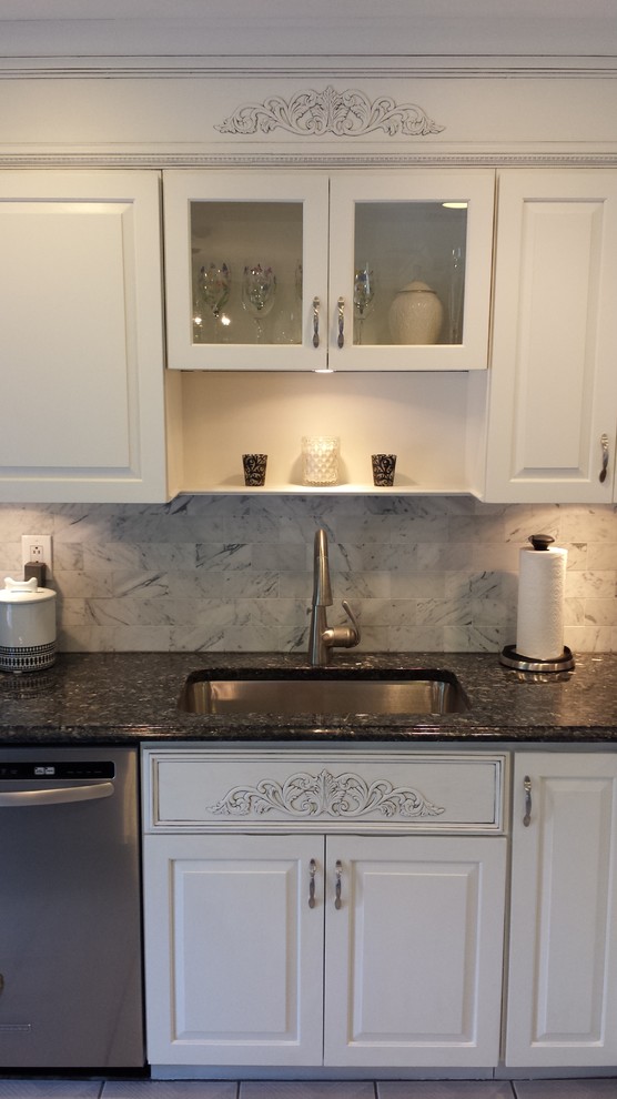 This is an example of a mid-sized transitional l-shaped eat-in kitchen in New York with an undermount sink, raised-panel cabinets, white cabinets, granite benchtops, white splashback, stone tile splashback, stainless steel appliances, ceramic floors and with island.