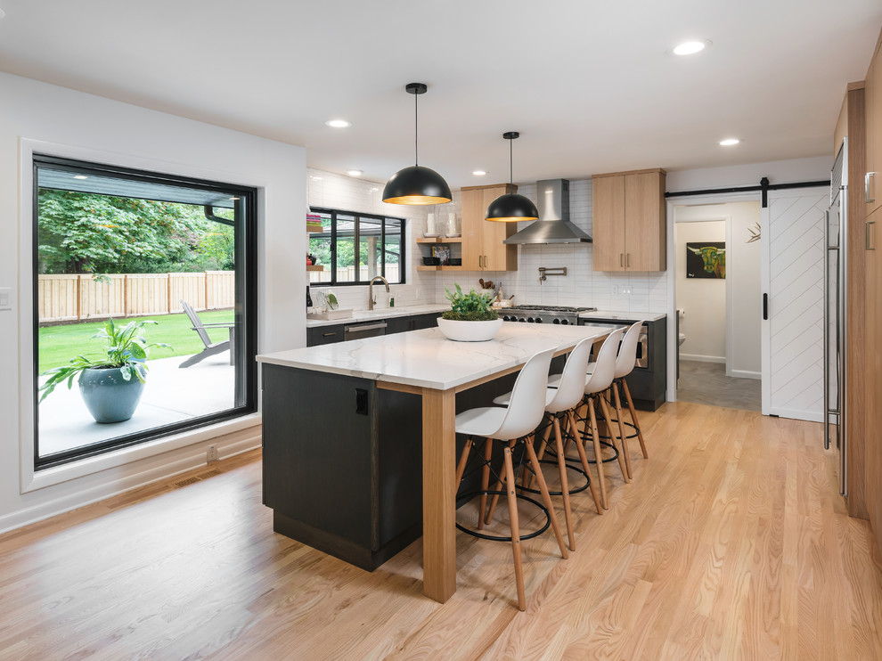 Design ideas for a contemporary u-shaped kitchen in Portland with an undermount sink, flat-panel cabinets, medium wood cabinets, white splashback, subway tile splashback, stainless steel appliances, medium hardwood floors, with island, brown floor and white benchtop.