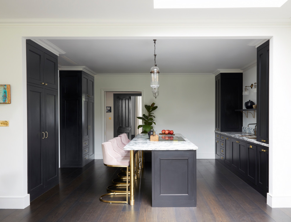 Photo of a large contemporary kitchen/diner in London with recessed-panel cabinets, black cabinets, marble worktops, white splashback, marble splashback, integrated appliances, dark hardwood flooring, an island, brown floors and white worktops.