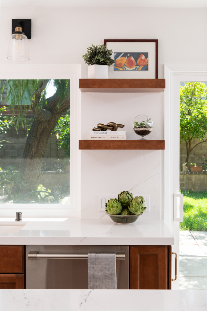 Example of a transitional porcelain tile and beige floor kitchen design in Orange County with an undermount sink, shaker cabinets, medium tone wood cabinets, quartz countertops, white backsplash, quartz backsplash, stainless steel appliances, an island and white countertops