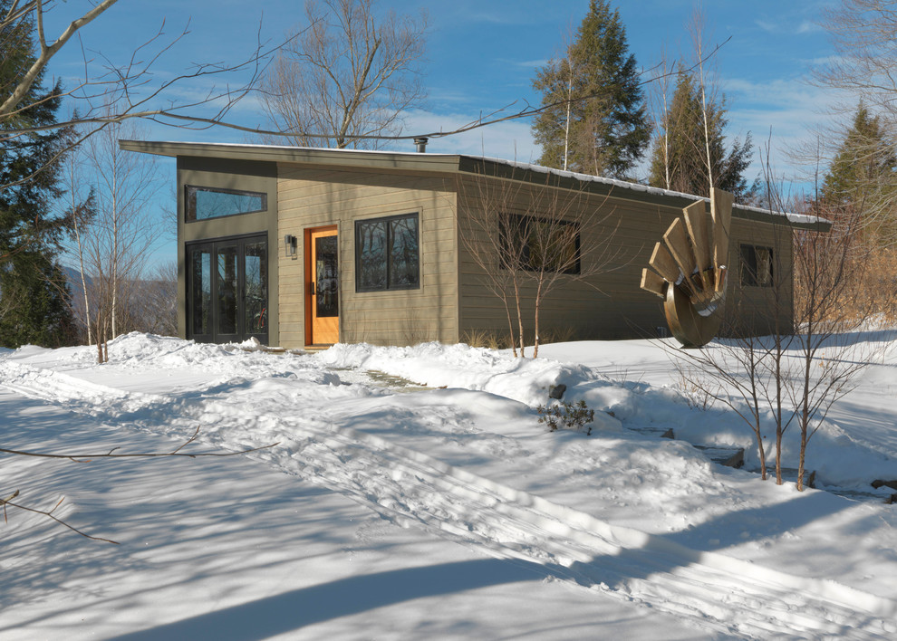 Small modern one-storey brown house exterior in Burlington with wood siding, a shed roof and a metal roof.