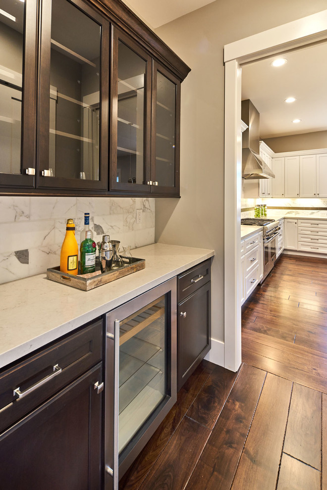 This is an example of a small transitional single-wall home bar in San Francisco with recessed-panel cabinets, dark wood cabinets, quartz benchtops, grey splashback, stone tile splashback and medium hardwood floors.