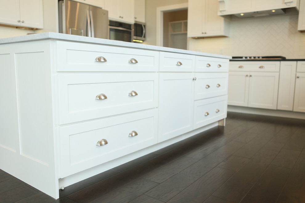 Eat-in kitchen - large transitional u-shaped dark wood floor eat-in kitchen idea in Chicago with a farmhouse sink, shaker cabinets, yellow cabinets, granite countertops, white backsplash, subway tile backsplash, stainless steel appliances and an island