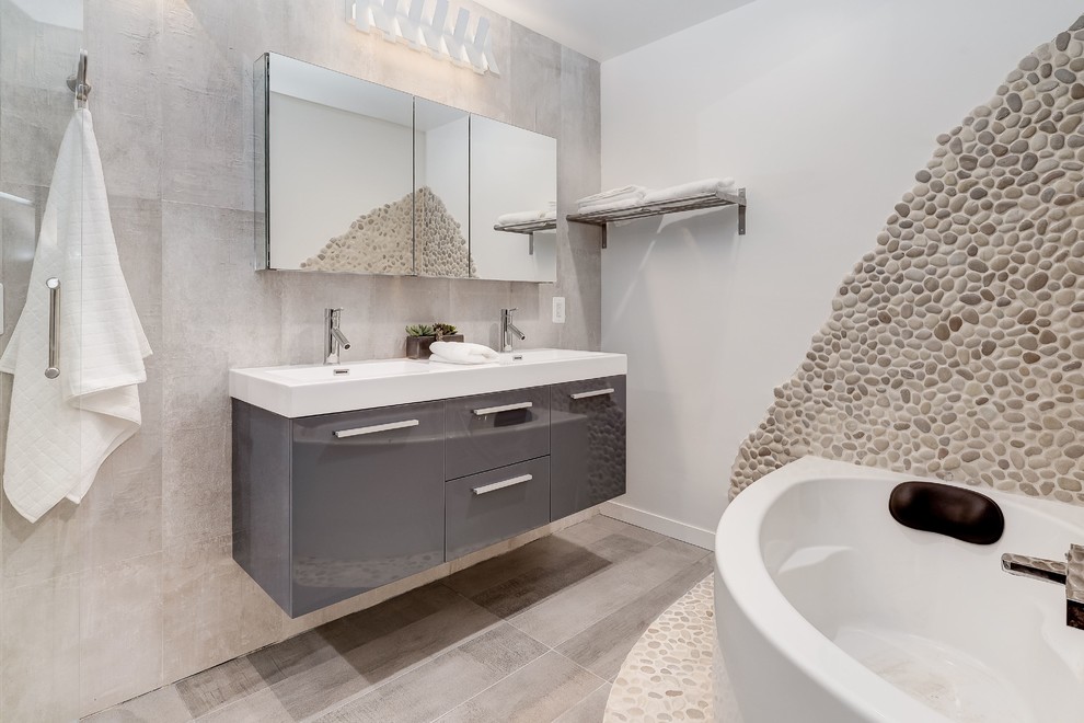 Inspiration for a mid-sized contemporary master bathroom in DC Metro with raised-panel cabinets, dark wood cabinets, a corner tub, an alcove shower, a one-piece toilet, beige tile, pebble tile, grey walls, medium hardwood floors, an integrated sink and solid surface benchtops.