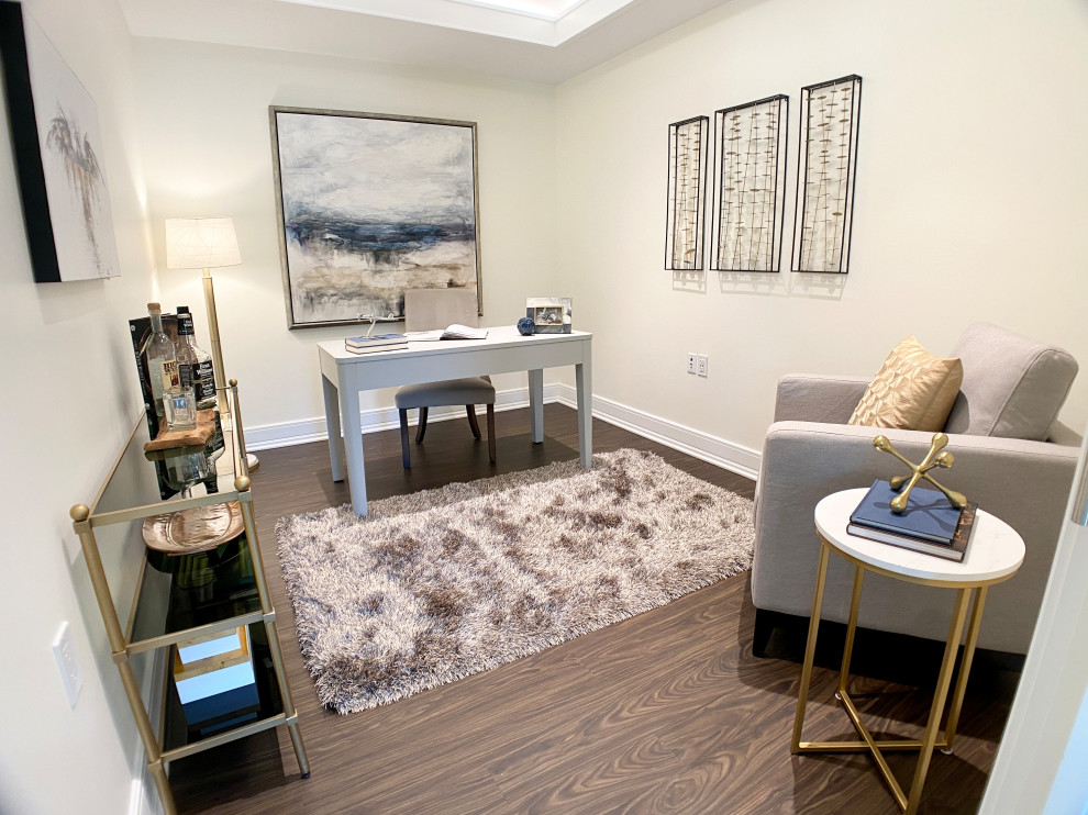 This is an example of a medium sized study in DC Metro with white walls, laminate floors, no fireplace, a freestanding desk and brown floors.