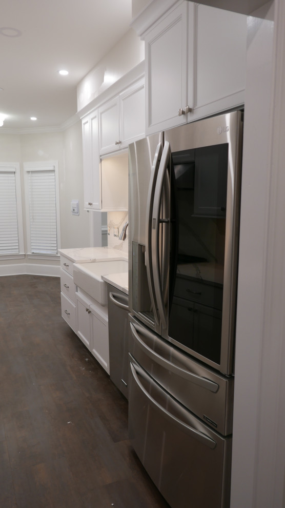Eat-in kitchen - mid-sized transitional galley laminate floor and brown floor eat-in kitchen idea with a farmhouse sink, shaker cabinets, white cabinets, quartz countertops, white backsplash, quartz backsplash, stainless steel appliances and white countertops