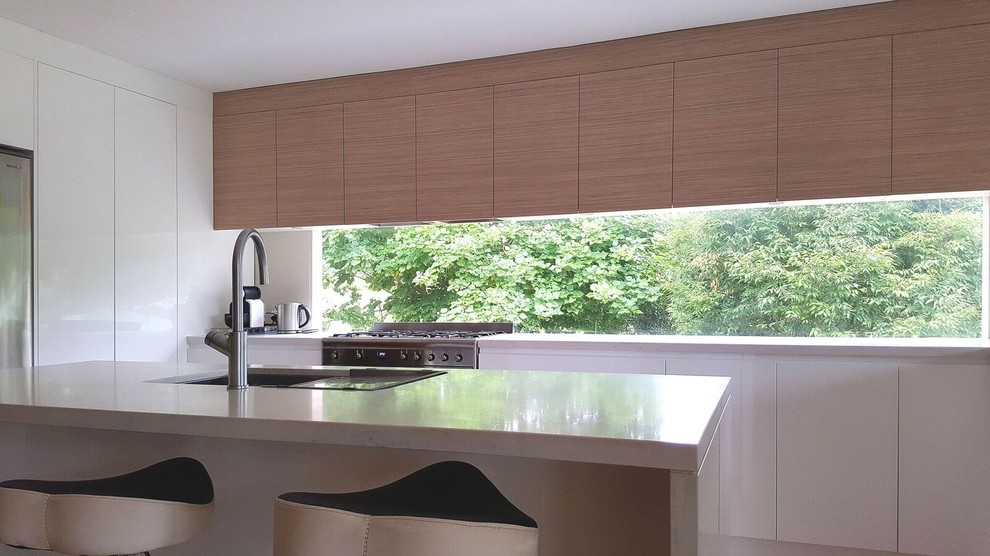 Photo of a large modern u-shaped eat-in kitchen in Sydney with an undermount sink, flat-panel cabinets, medium wood cabinets, quartz benchtops, window splashback, stainless steel appliances, light hardwood floors and with island.