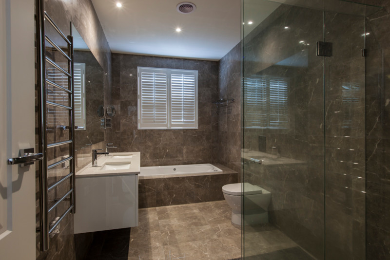 Photo of a mid-sized contemporary bathroom in Melbourne with an alcove tub, a wall-mount toilet, brown tile, marble, brown walls, marble floors and brown floor.
