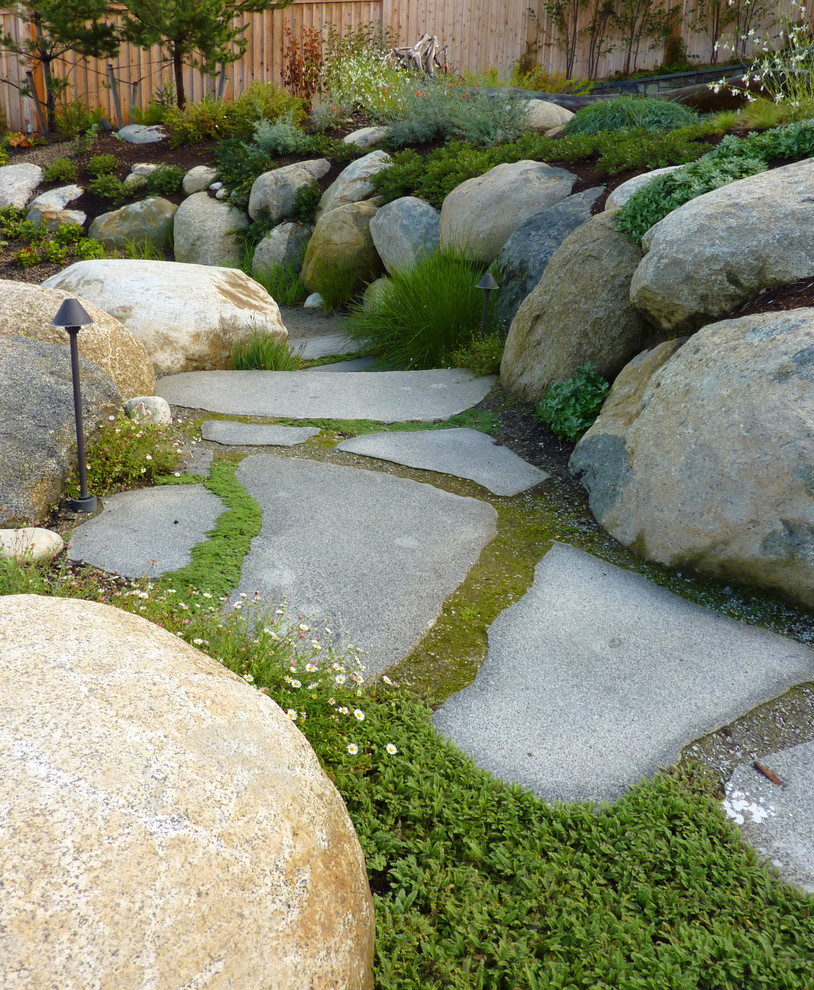 Photo of a mid-sized beach style backyard partial sun garden in Seattle with natural stone pavers and a retaining wall.