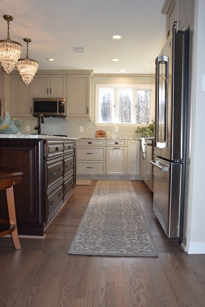 Photo of a mid-sized traditional u-shaped eat-in kitchen in Baltimore with an undermount sink, recessed-panel cabinets, beige cabinets, limestone benchtops, white splashback, ceramic splashback, stainless steel appliances, dark hardwood floors, with island, brown floor and beige benchtop.