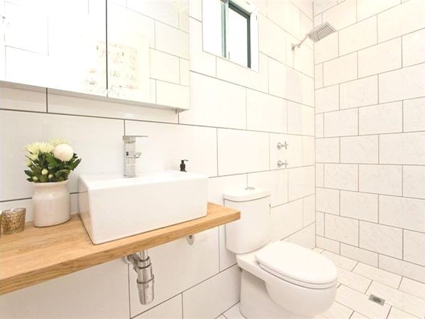 Photo of a small contemporary bathroom in Dunedin with a vessel sink, open cabinets, light wood cabinets, wood benchtops, an open shower, a one-piece toilet, white tile, ceramic tile, white walls and marble floors.
