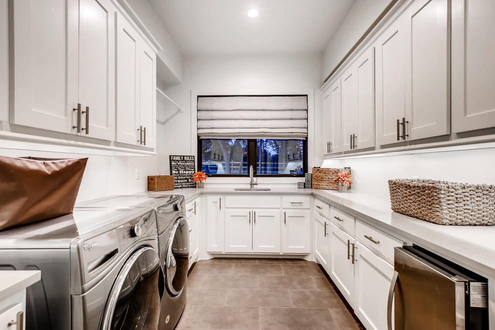 Design ideas for a large contemporary galley dedicated laundry room in Austin with a single-bowl sink, beaded inset cabinets, grey cabinets, soapstone benchtops, white walls, terra-cotta floors, a side-by-side washer and dryer, brown floor and grey benchtop.