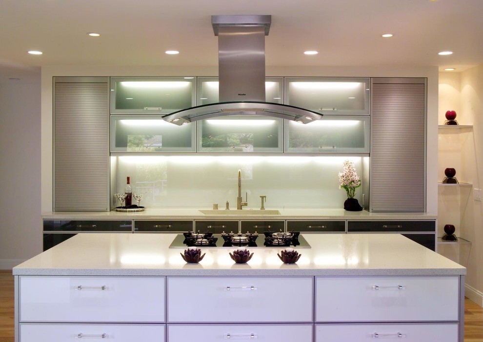 Inspiration for a contemporary l-shaped kitchen in San Francisco with an undermount sink, flat-panel cabinets, black cabinets, quartz benchtops, white splashback, stainless steel appliances, light hardwood floors and with island.