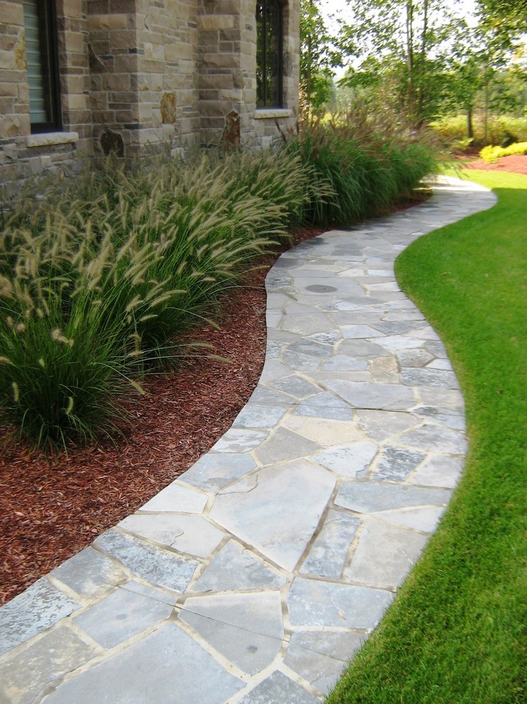 This is an example of a large traditional side yard partial sun garden in Toronto with natural stone pavers.