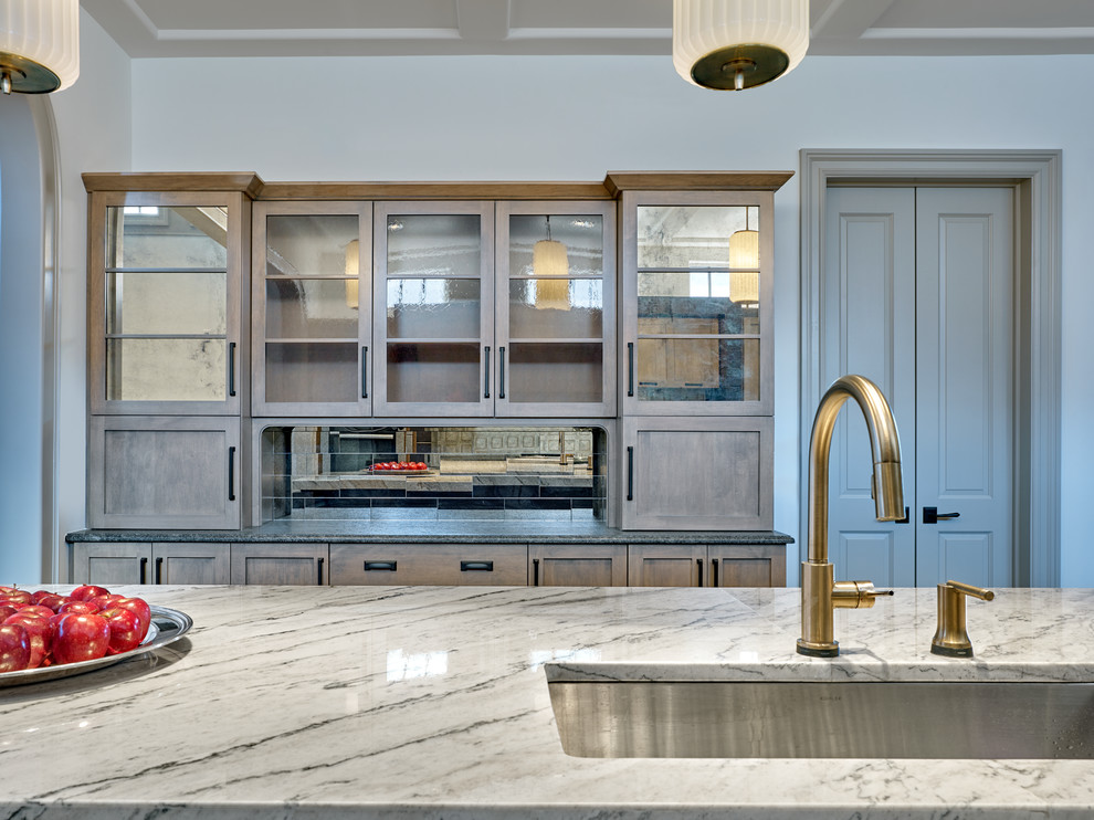 This is an example of a large country single-wall kitchen in Philadelphia with a farmhouse sink, shaker cabinets, medium wood cabinets, quartzite benchtops, white splashback, marble splashback, stainless steel appliances, medium hardwood floors, multiple islands, brown floor and white benchtop.
