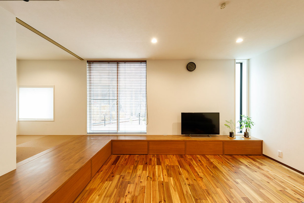 This is an example of a mid-sized industrial formal open concept living room in Tokyo Suburbs with white walls, dark hardwood floors, a freestanding tv, brown floor, wallpaper and wallpaper.