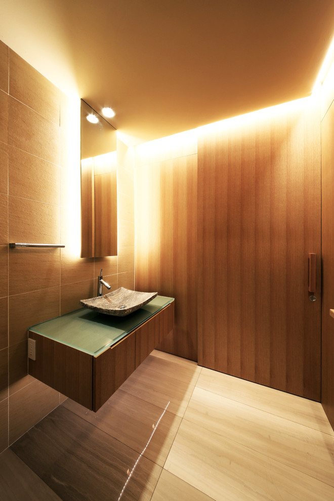 Inspiration for a large modern powder room in Tokyo Suburbs with a one-piece toilet, brown tile, cement tile, brown walls, marble floors, glass benchtops and beige floor.