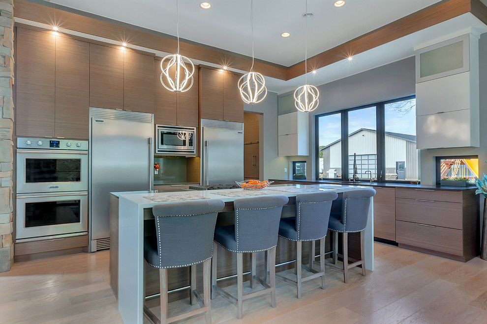 Example of a large trendy l-shaped light wood floor and beige floor open concept kitchen design in Minneapolis with flat-panel cabinets, medium tone wood cabinets, quartzite countertops, stainless steel appliances, an island, window backsplash and an undermount sink