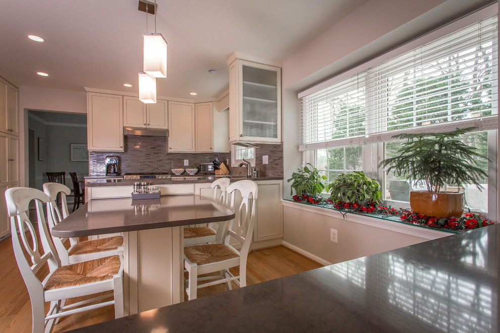 Inspiration for a transitional u-shaped light wood floor kitchen remodel in DC Metro with an undermount sink, flat-panel cabinets, white cabinets, quartz countertops, gray backsplash and stainless steel appliances