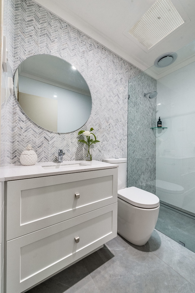 Photo of a small contemporary master bathroom in Perth with shaker cabinets, white cabinets, an open shower, a one-piece toilet, multi-coloured tile, mosaic tile, multi-coloured walls, porcelain floors, an undermount sink, solid surface benchtops, grey floor, an open shower and white benchtops.