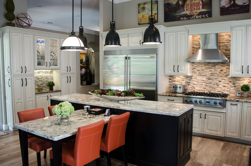 Large transitional l-shaped porcelain tile open concept kitchen photo in Miami with a farmhouse sink, raised-panel cabinets, white cabinets, granite countertops, multicolored backsplash, mosaic tile backsplash, stainless steel appliances and an island