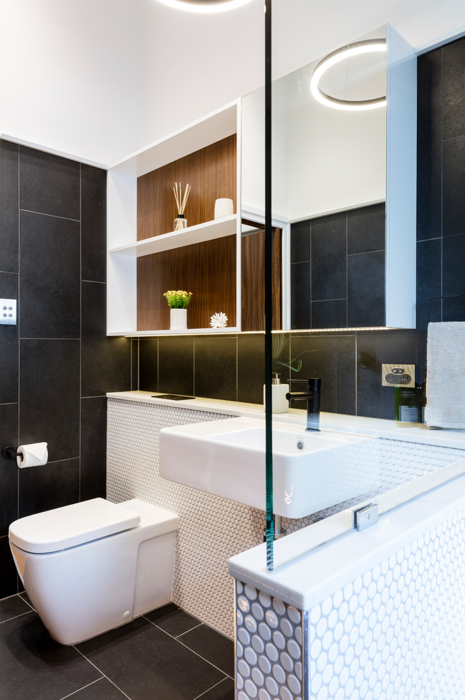 Small modern kids bathroom in Brisbane with open cabinets, white cabinets, an open shower, a one-piece toilet, black and white tile, porcelain tile, black walls, porcelain floors, a pedestal sink, wood benchtops, black floor and an open shower.
