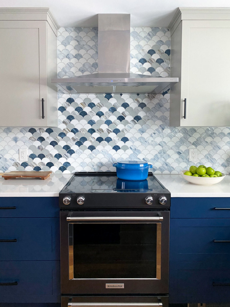 Design ideas for a transitional eat-in kitchen in Boston with an undermount sink, shaker cabinets, blue cabinets, quartz benchtops, multi-coloured splashback, mosaic tile splashback, black appliances, medium hardwood floors, with island and white benchtop.