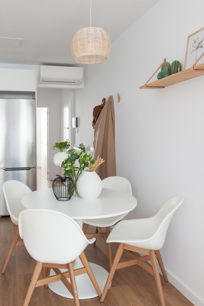 This is an example of a small scandinavian open plan dining in Madrid with white walls, dark hardwood floors and brown floor.