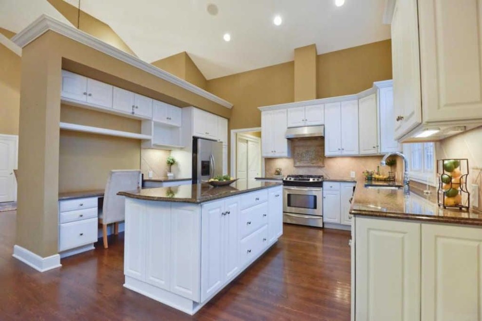 Inspiration for a large traditional l-shaped eat-in kitchen in Columbus with an undermount sink, white cabinets, granite benchtops, black appliances, medium hardwood floors, a peninsula, brown floor, brown benchtop, raised-panel cabinets, beige splashback and ceramic splashback.