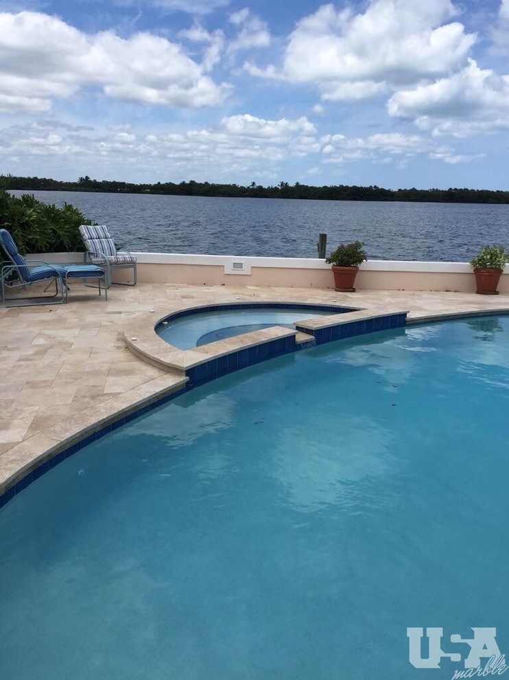 This is an example of a mid-sized backyard aboveground pool in Miami with natural stone pavers.