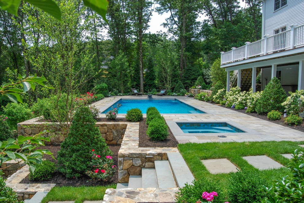 Inspiration for a large traditional backyard rectangular pool in Boston with natural stone pavers and a hot tub.