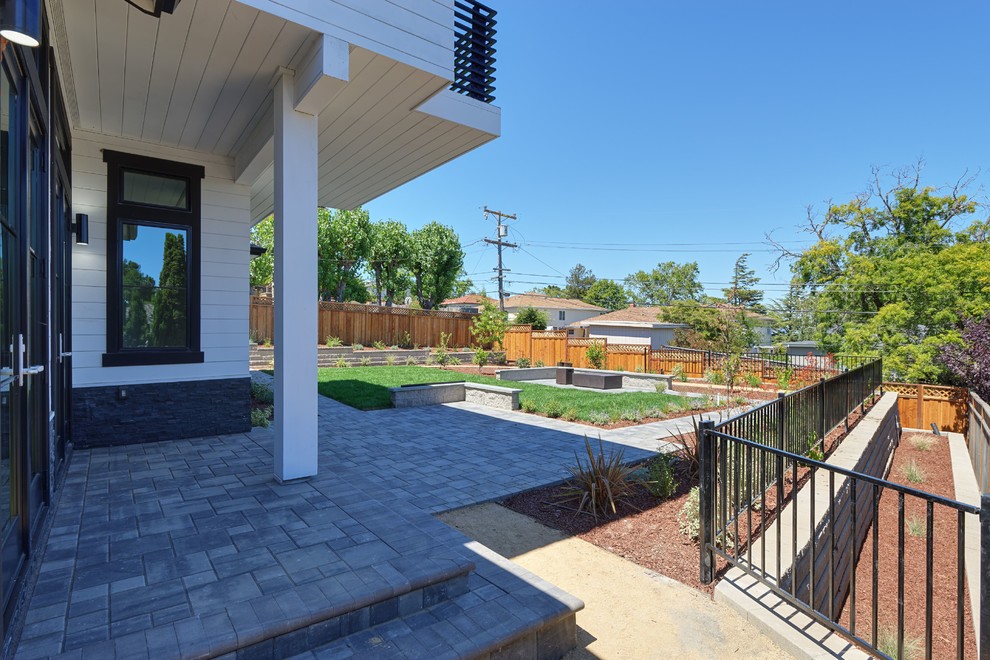 This is an example of a large transitional backyard patio in San Francisco with concrete pavers and a roof extension.
