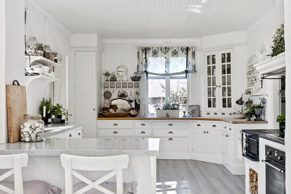 This is an example of a traditional u-shaped kitchen in Other with glass-front cabinets, white cabinets and a peninsula.