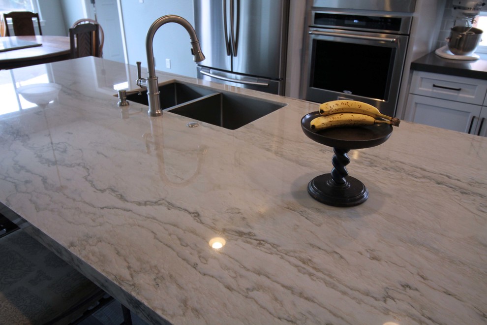 Mid-sized transitional l-shaped porcelain tile open concept kitchen photo in Sacramento with an undermount sink, shaker cabinets, gray cabinets, quartzite countertops, gray backsplash, ceramic backsplash, stainless steel appliances and an island