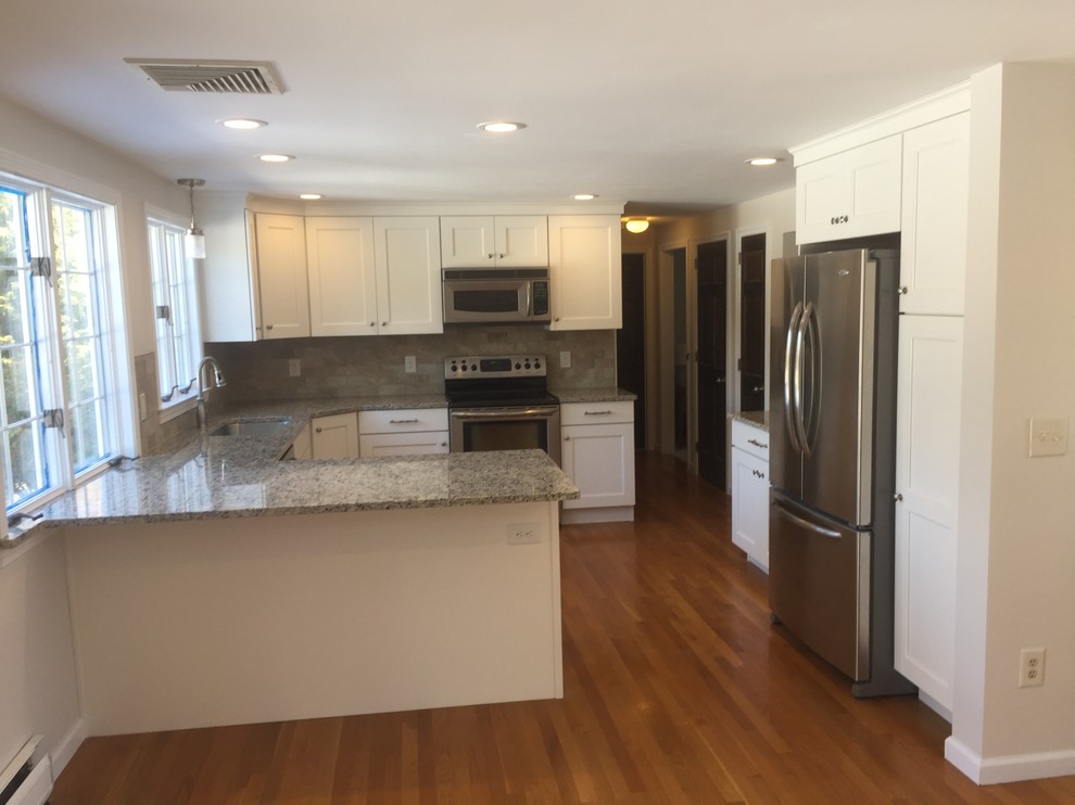 This is an example of a mid-sized traditional u-shaped eat-in kitchen in New York with an undermount sink, shaker cabinets, white cabinets, granite benchtops, beige splashback, porcelain splashback, stainless steel appliances, light hardwood floors and with island.