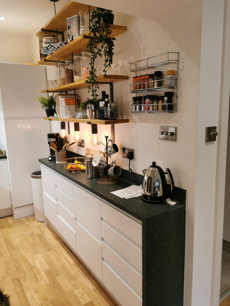 Photo of a small industrial single-wall separate kitchen in Kent with white cabinets, green splashback and stainless steel appliances.