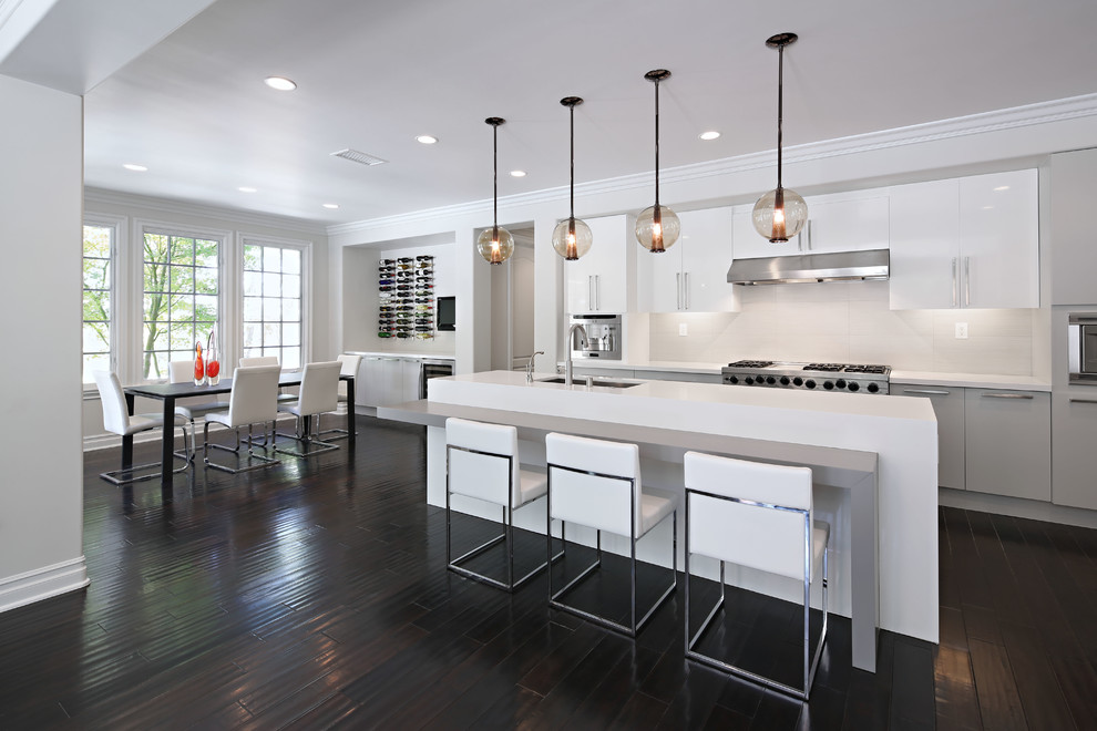 Design ideas for a large contemporary galley open plan kitchen in Los Angeles with flat-panel cabinets, white cabinets, white splashback, stainless steel appliances, an undermount sink, quartz benchtops, porcelain splashback, dark hardwood floors and with island.