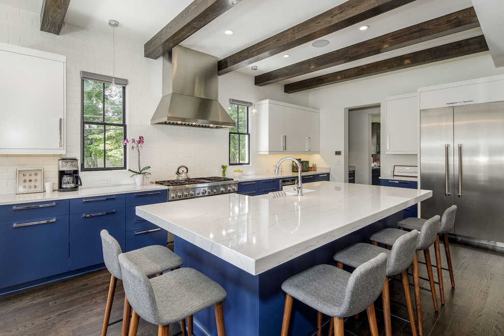 Inspiration for a contemporary l-shaped kitchen in Atlanta with an undermount sink, flat-panel cabinets, blue cabinets, solid surface benchtops, white splashback, brick splashback, stainless steel appliances, dark hardwood floors, with island and white benchtop.