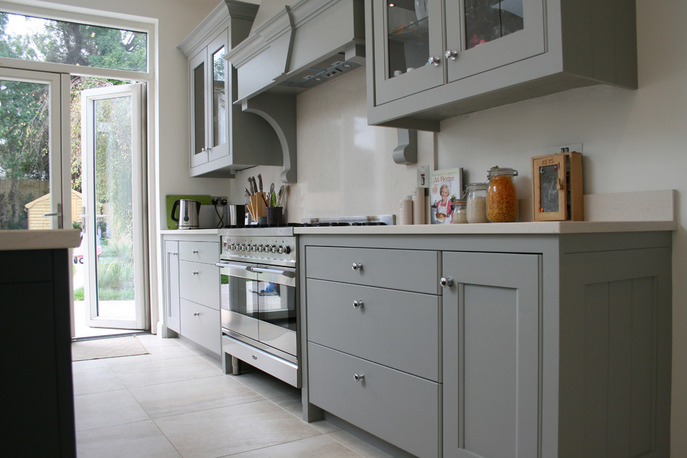 Photo of a transitional single-wall eat-in kitchen in Dublin with a farmhouse sink, glass-front cabinets and grey cabinets.