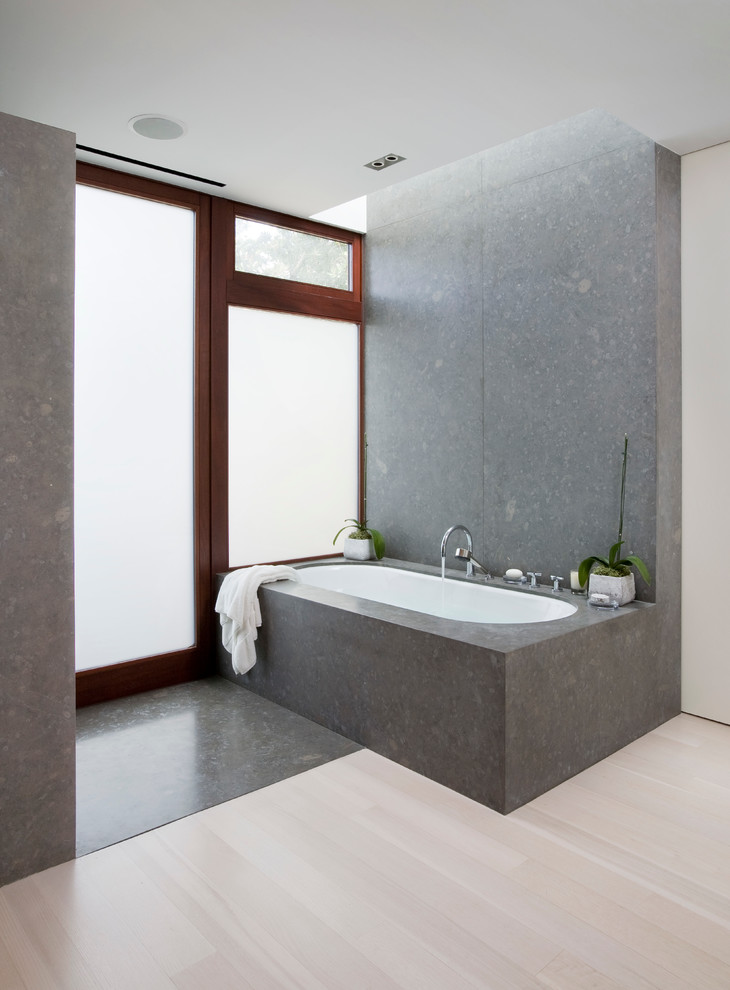 Example of a trendy light wood floor bathroom design in Los Angeles with an undermount tub and gray walls