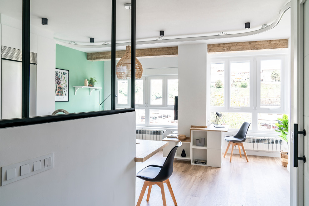 Пример оригинального дизайна: гостиная комната среднего размера, в белых тонах с отделкой деревом в скандинавском стиле с зелеными стенами, полом из винила, телевизором на стене и балками на потолке