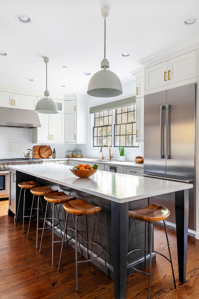 This is an example of a mid-sized beach style l-shaped kitchen in Chicago with an undermount sink, shaker cabinets, white cabinets, quartz benchtops, white splashback, stainless steel appliances, medium hardwood floors, with island, white benchtop and subway tile splashback.